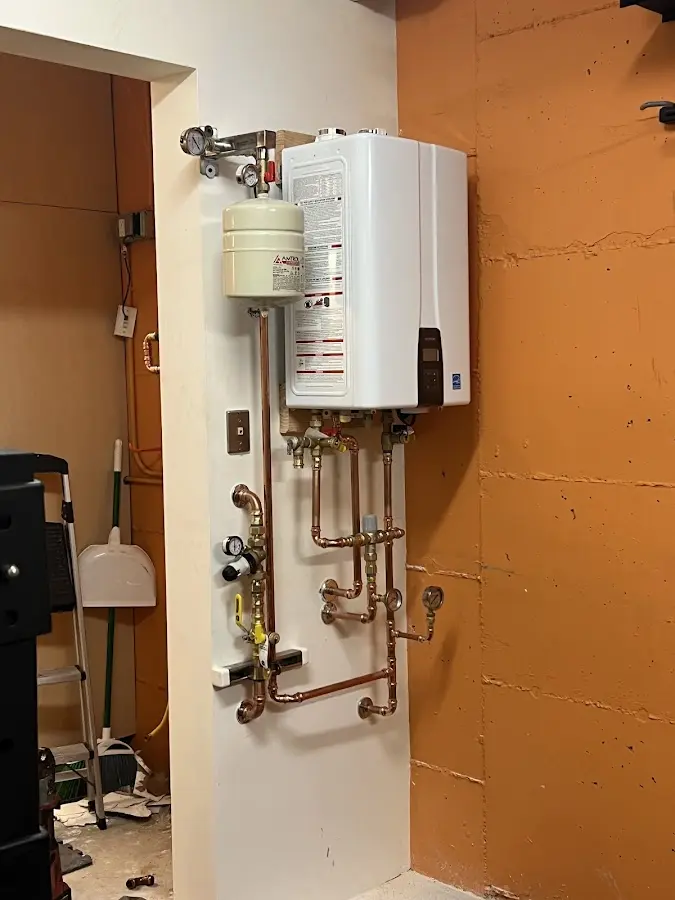 Plumbing technician inspecting water heater connections in Brent